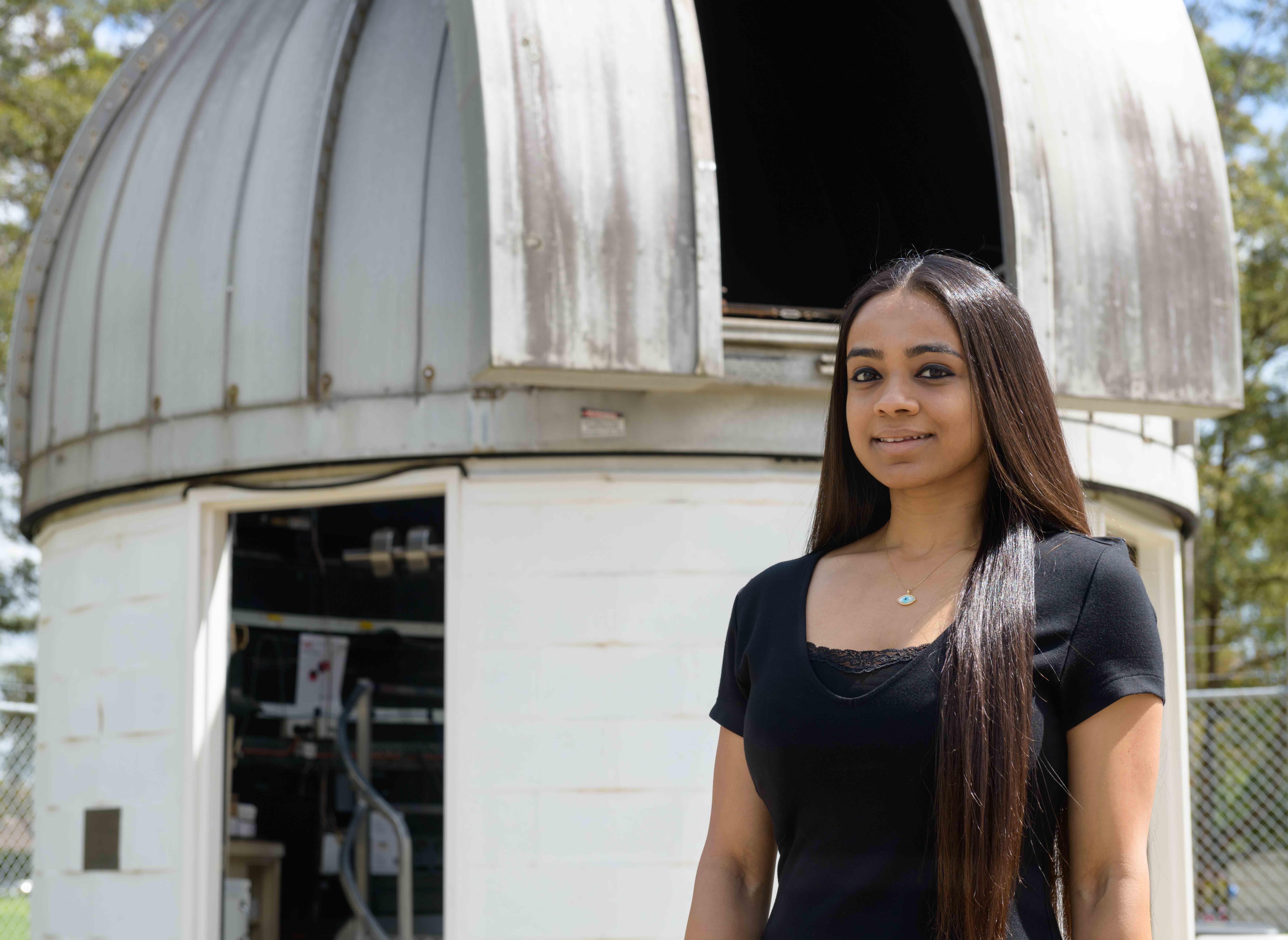 Dr Devika Kamath standing in front of a stellar observatory